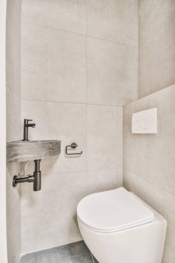 Duvarlarında gri fayanslar olan bir banyoda beyaz bir tuvalet ve arkasına monte edilmiş bir parmaklık.