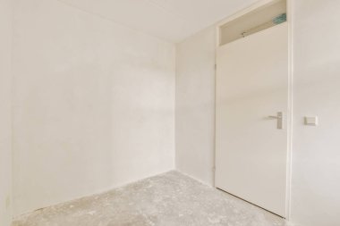 Beyaz duvarları olan boş bir oda ve diğer duvarda hiç kapı yok. Köşede küçük bir pencere var.