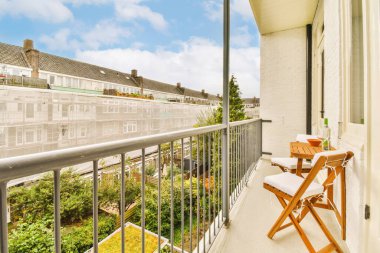 Sol tarafında sandalye ve masa olan bir balkon. Dışarıdan şehre bakıyor.