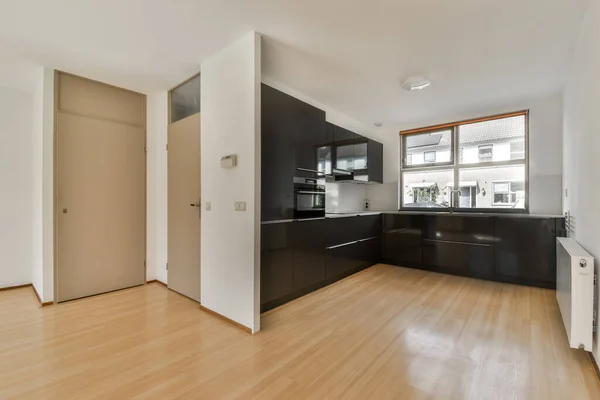 an empty kitchen and dining area in a house with wood floors, white walls and black cabinetd cupboards