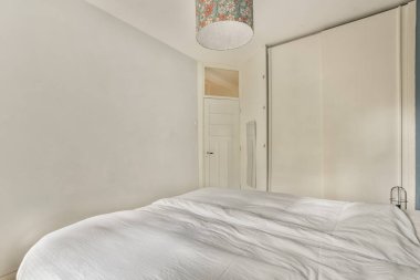 a bedroom with a bed and a lamp on the ceiling light is attached to the wall above the headboard