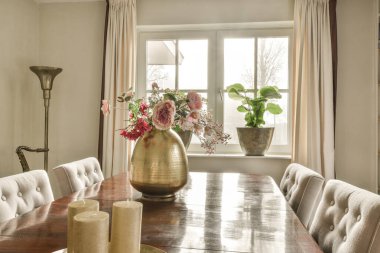 a dining room table with vases and flowers in the center, on top of it is a large window