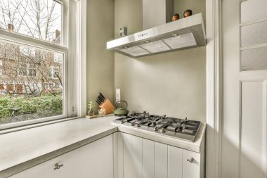 a kitchen with white cabinets and counter space in front of the window that looks out onto an urban neighborhood street