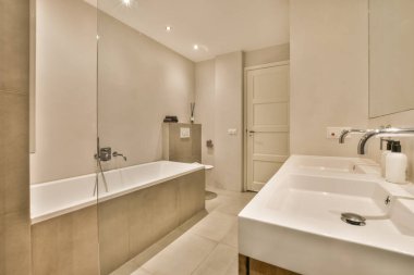 Odanın ortasında lavabo ve küveti olan bir banyo duvarda bir ayna var.