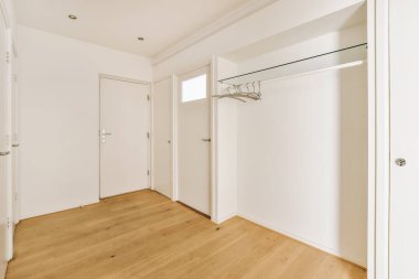 an empty room with white walls and wood flooring on the left, there is a mirror in the door