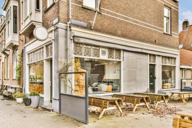 an outside area with tables and chairs on the sidewalk in front of a building that is being used as a coffee shop