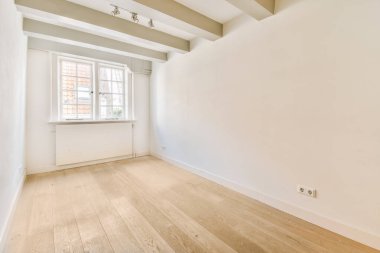 Beyaz duvarları ve ahşap döşemeleri olan boş bir oda. Köşesinde küçük bir pencere var.