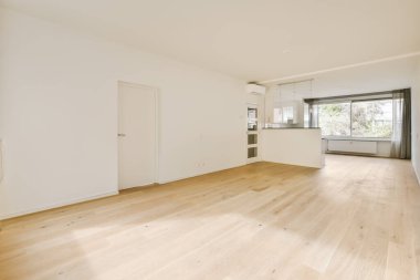 Odasında ahşap döşeme ve beyaz duvarlar olan boş bir oturma odası çok temiz, ama mobilya yok.