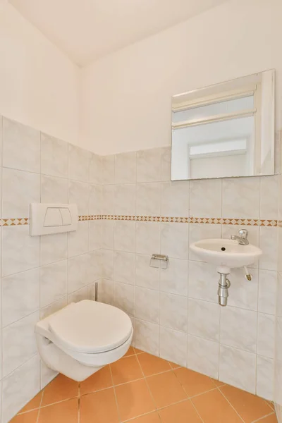 a bathroom with tile flooring and white tiles on the walls, there is a mirror above the toilet bowl