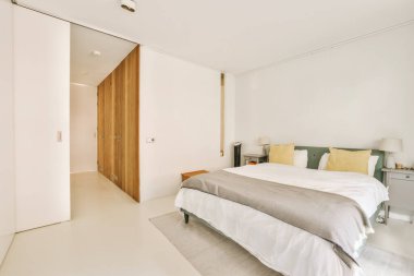 Modern bir yatak odası, beyaz duvarlar ve ahşap kapılar. Dışarıya açılan kapılar. İçerisi de öyle.