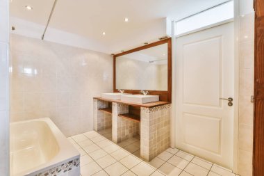 Lavabosu, aynası ve küveti olan bir banyo odanın kapısının önünde.