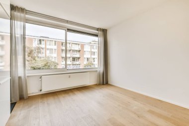 an empty living room with wood flooring and large windows looking out onto the street in front of the apartment