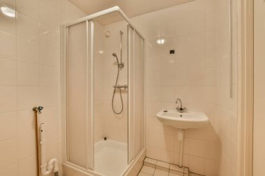 Lavabosu, duşu ve tuvaleti olan bir banyo diğer duvarda aynı odada bir ayna var.