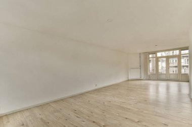 an empty room with white walls and wood flooring in the middle part of the room there is a large window