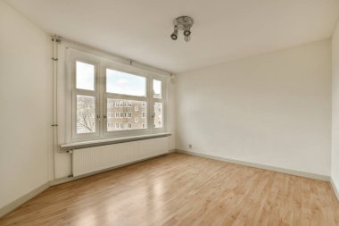 an empty room with wood flooring and white paint on the walls there is a window that looks out onto the street