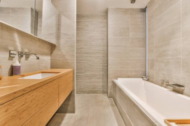 Küveti, lavabosu ve aynası olan bir banyo. Duş kabininin yanındaki küvetin yanında.