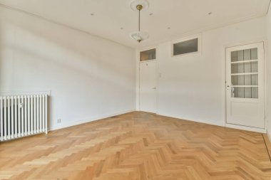 an empty room with white walls and wood flooring on the right side, there is a radiac heater in the