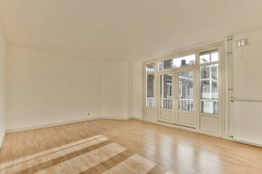 an empty living room with wood flooring and large sliding doors leading out to the balcony area in this apartment