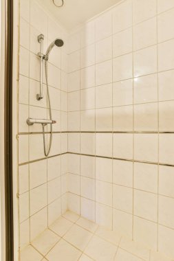 a white tiled bathroom with shower head and hand held in the shower arm to keep it from getting dirty water