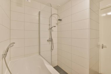 a bathroom with a bathtub and shower head in the corner next to the tub, there is a glass door on the wall