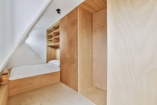an attic bedroom with wooden walls and white walls, there is a small bed in the room has built into the wall