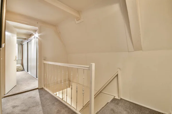 an empty room with no one on the stairs or railings, and there is a staircase leading up to the second floor