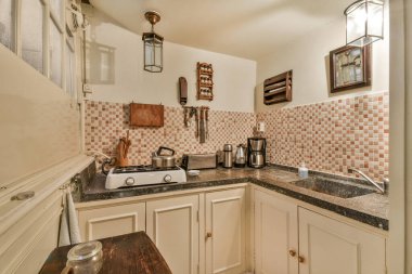 a kitchen with white cabinets and black counter tops on the countertop, in front of a sink that is off to the right