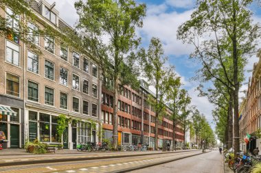 Amsterdam 'da boş bir cadde, yan tarafında motosikletler ve ortada yürüyen insanlar.