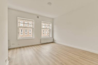 Ahşap döşemeli boş bir oda ve apartmanın önündeki sokağa bakan iki pencere.