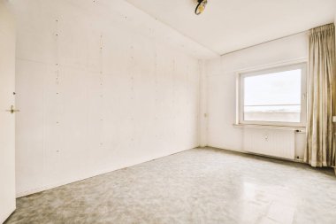 an empty room with white walls and peeling paint on the walls, there is a window in the wall that looks out to the