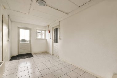 an empty room with white walls and tile flooring on either side, there is a door to the left