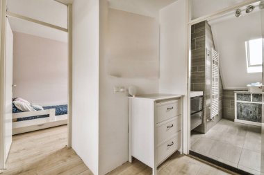 a bathroom with wood flooring and white cabinets in the corner, next to a walk - in shower stall