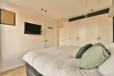 a bedroom with a bed, television and tv mounted above the headboard is on the wall in the room