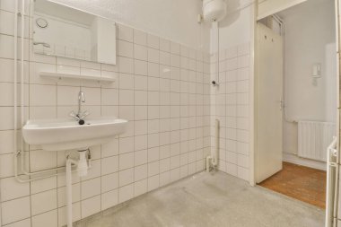 a small bathroom with white tiles on the walls and floor, including a sink and mirror in the corner area