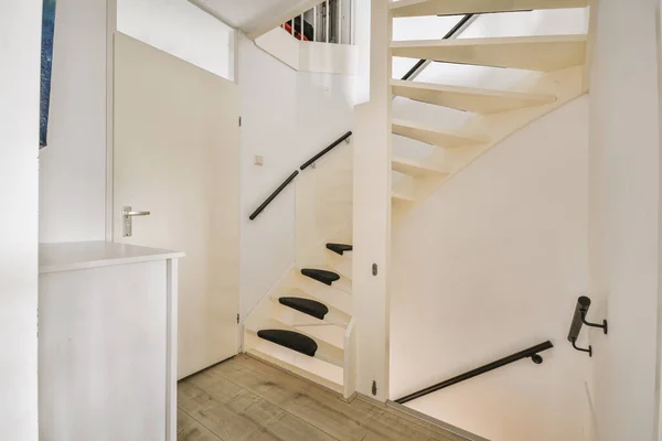 a room with stairs and an open door in the center of the room is a staircase leading up to the second floor