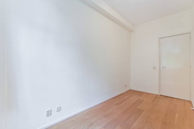 an empty room with wood flooring and white paint on the walls there is a door that leads to another room