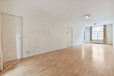 an empty room with wood floors and white walls, there is a large window in the wall to the right