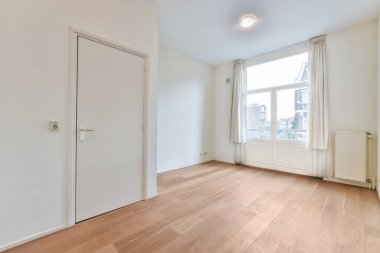 an empty room with wood flooring and white walls, there is a door that leads to another room in the room