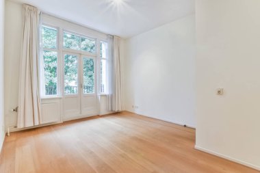 an empty room with wooden floors and white walls, there is a large window in the wall to the right