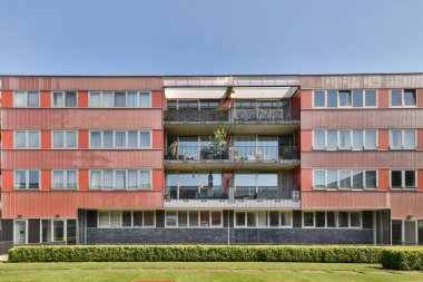 Amsterdam, Netherlands - 10 April, 2021: an apartment building with many windows and bales on the top floor, as seen from the street in front