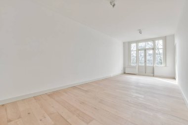 an empty room with white walls and wood flooring on the right side of the room, there is a large window in the