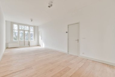 an empty room with white walls and wood flooring in the center of the room, there is a door that leads to another