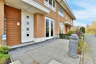 a house with a mailbox in the front and some plants on the sidewalk next to the door is open