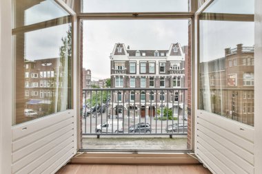 an open window with the view of a street and buildings in the distance, taken from inside one of the windows