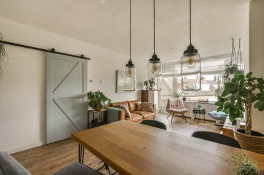 Amsterdam, Netherlands - 10 April, 2021: a dining room with some plants on the table and an open sliding door in the back wall to the right