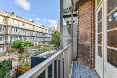 an outside area with some plants and buildings in the background, as seen from a balcony or other building on a sunny day