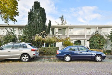 Amsterdam, Netherlands - 10 April, 2021: some cars parked in front of a brick building with many windows on the top and bottom part of the building