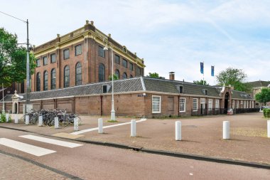 an old brick building on the side of a street with bicycles parked in front and two people walking down the sidewalk