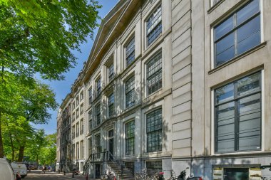 Amsterdam, Netherlands - 10 April, 2021: a city street with bicycles parked on the curbs and people walking down the sidewalk in front of some buildings