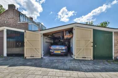 a garage with a car parked in the door and two doors open on either side of the garage are brick walls